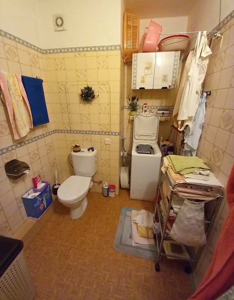 Původní koupelna před rekonstrukcí – žlutý obklad, WC a pračka
