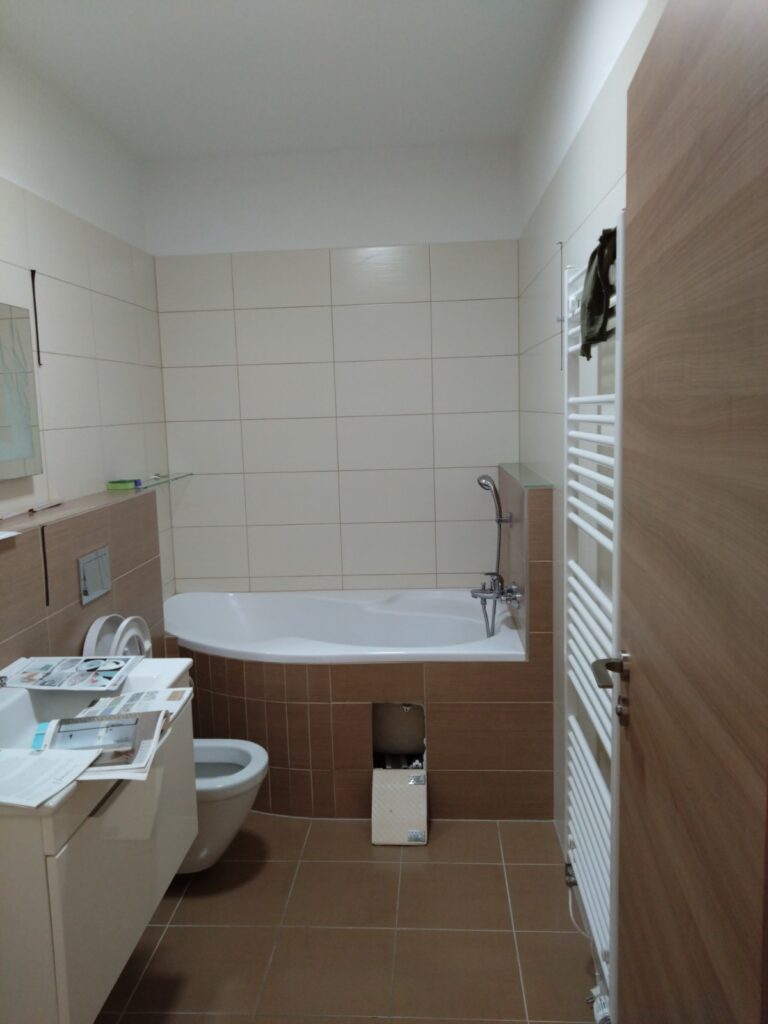 Původní koupelna před rekonstrukcí – béžový obklad, vana a bidet