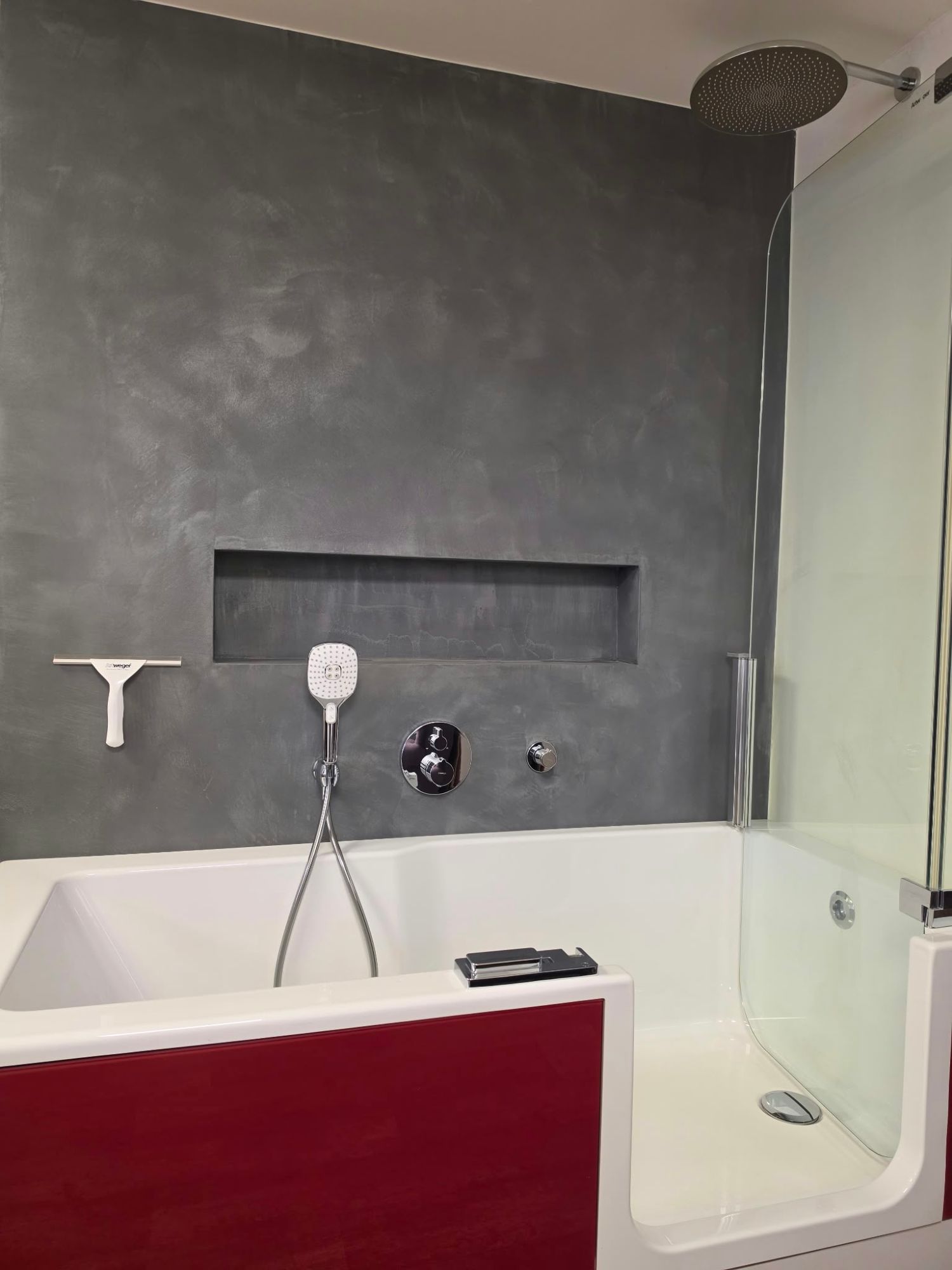 Koupelna s dekorační stěrkou JUB HYDROSOL Decor – celistvá šedá stěna bez spár a vana se sprchovým koutem