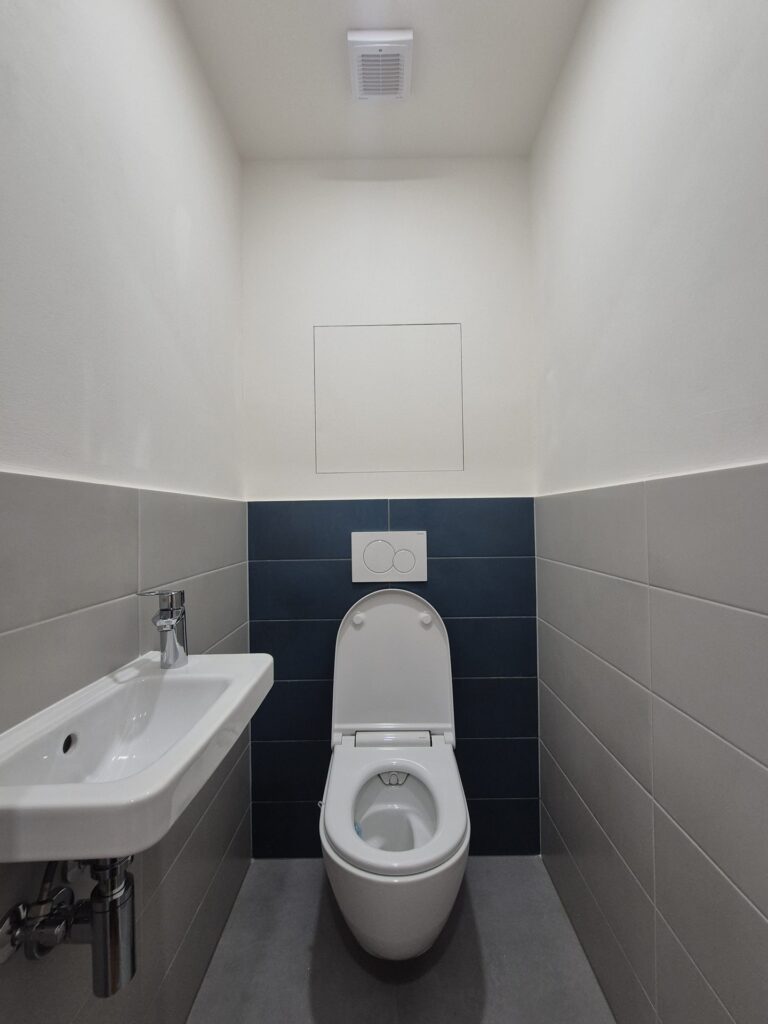 Samostatné WC se závěsnou mísou a modrošedým obkladem, rekonstrukce Praha Kamýk
